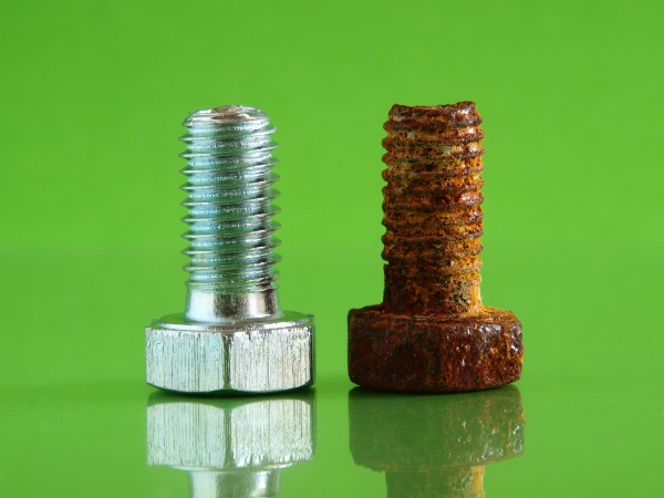 Vergleich einer neuen und einer korrodierten Stahlschraube korrosion