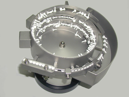 Vibrationswendelförderer: Werkstücke werden durch Vibrationen spiralförmig nach oben bewegt. Nicht korrekt ausgerichtete Bauteile fallen aufgrund der vorgegebenen Geometrie zurück in die Schale.